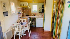 Cozinha compacta com área de refeições, apresentando um painel de azulejos, um fogão e um micro-ondas.