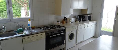 A kitchen with a gas stove, oven, microwave, and a washing machine.