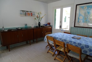A dining area with a table set for four, wooden chairs, a vase with flowers, and a map on the wall.