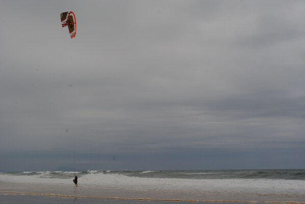 Una playa con una persona volando una cometa.