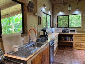 A kitchen with wooden cabinets, a sink, a microwave, a toaster, and a window with a view of greenery.