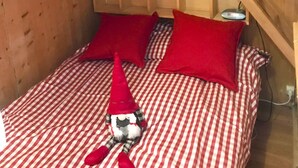 Un acogedor dormitorio de cabaña de madera con literas, ropa de cama de cuadros y una decoración de gnomo.