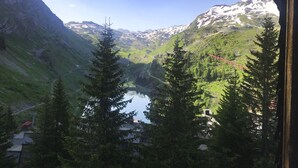 Paisaje montañoso con un lago, árboles y un puente rojo.