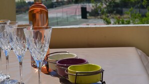 Una mesa con copas de vino y una botella, con vistas a un paisaje costero.