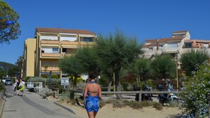 Zona residencial costera con edificios de varios pisos, un paseo pavimentado y vehículos estacionados.