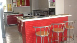 A kitchen with red and white cabinets, a central island with bar stools, and a microwave above the island. - Superb accommodation in a green location with private pool. (Sainte Anne)