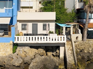 Un bâtiment situé sur la côte, doté d’un balcon, de murs en pierre et d’un escalier en pierre menant à une porte portant l’inscription « PENA ».