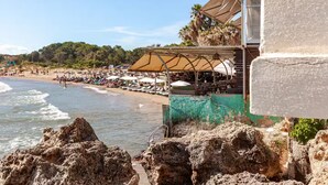 A coastal view with a beach, umbrellas, and a rocky foreground. - Villa Rena by the sea! (Arkoudi)