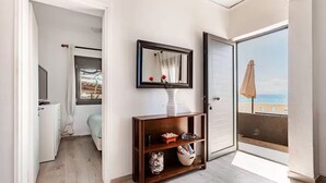 A modern apartment with a balcony, a wooden console table, a framed mirror, and a view of the city. - Villa Rena by the sea! (Arkoudi)