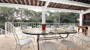 An outdoor patio with a round table, white metal chairs, a red flower pot, and a fire extinguisher. - PROVENCAL MAS PISICINE JACUZZI CLIM 10 PEOPLE (JUAN LES PINS)