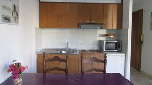 A compact kitchen with wooden cabinets, a microwave, and a sink.