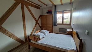 Une chambre avec un lit en bois, une fenêtre donnant sur un beau paysage et une armoire.