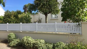 A white house with a white fence, surrounded by greenery and a clear blue sky. - House Heart LOCTUDY - Close Sea and Beach on foot. (Loctudy)