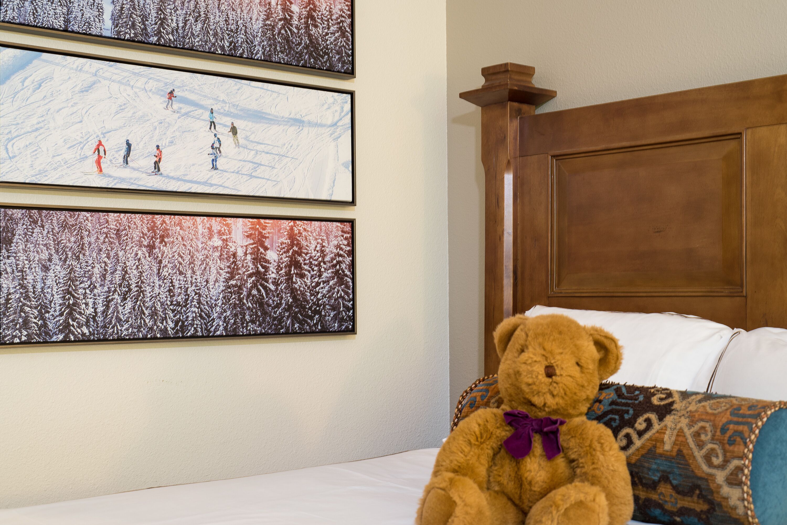 A room with a bed, a wooden headboard, and three framed pictures on the wall.