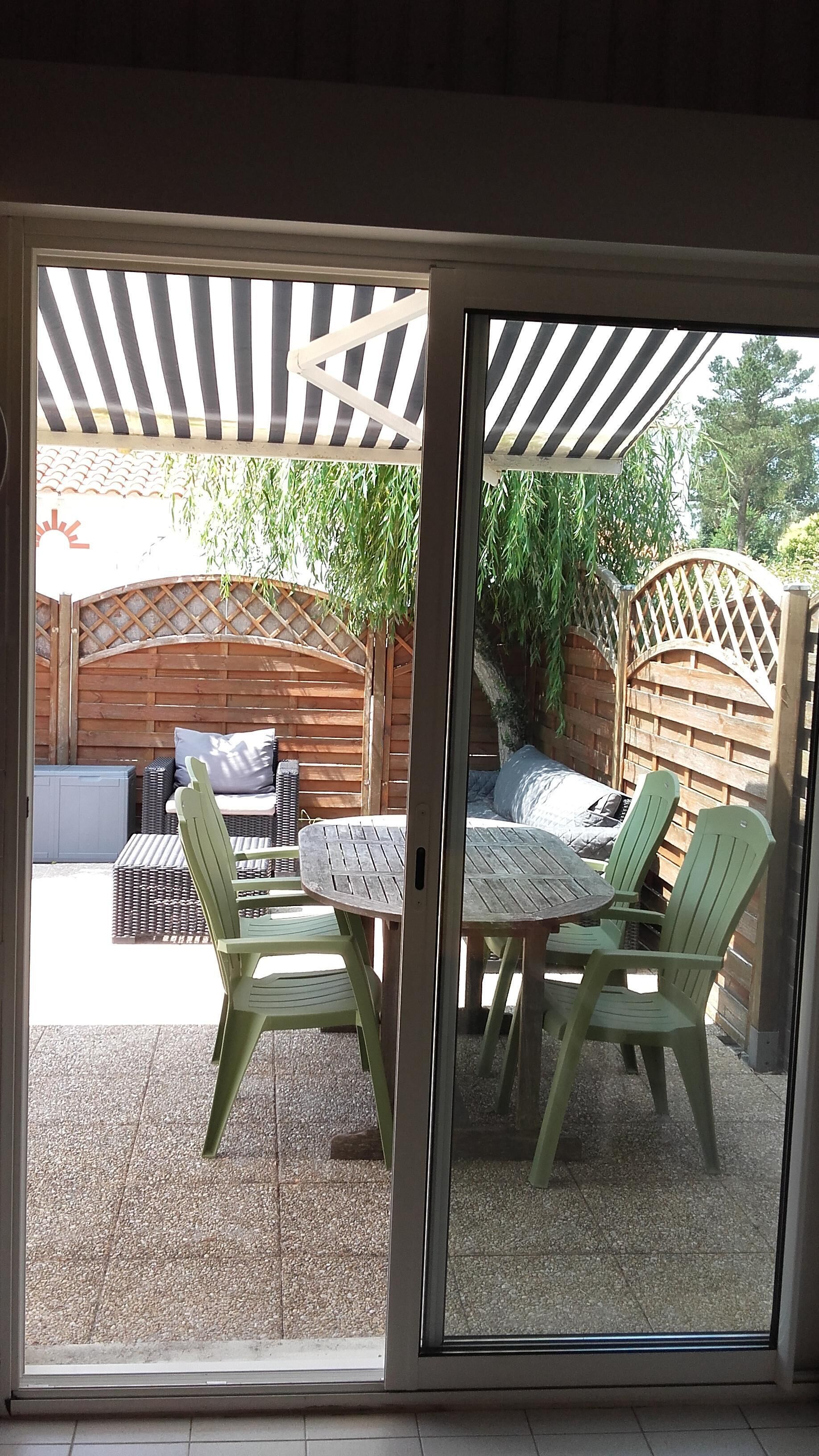 Eine Terrasse mit überdachter Sitzgelegenheit, einem Tisch und Stühlen.