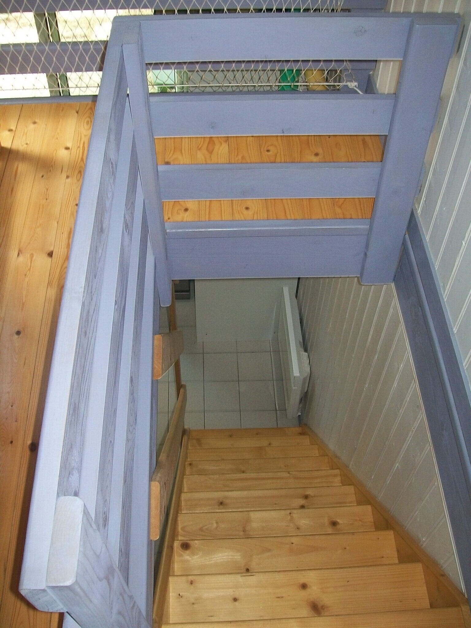 A wooden staircase with a metal railing, leading to a lower level.
