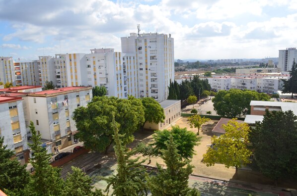A high-rise residential building with multiple balconies, surrounded by trees and other buildings. - APARTMENT 85 M2 - RENOVATED - 6 PEOPLE (Jerez de la Frontera)