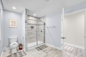 A bathroom with a toilet, shower, and a glass-enclosed shower area. - The Grand Ranch: 6-BR Luxury Retreat with with Gazebo, Fire Pit & Outdoor Cinema (Raleigh)