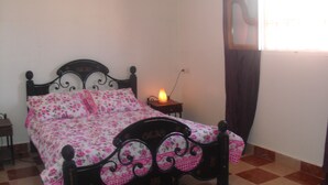 A bed with floral bedding, a nightstand with a lamp, and a checkered floor.