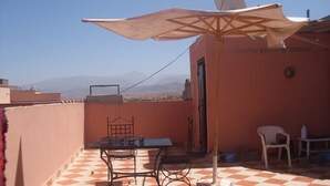 A terrace with a table and chairs, a satellite dish, and a view of distant mountains.