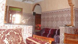 A room with a patterned sofa, a wooden headboard, and a ceiling fan.