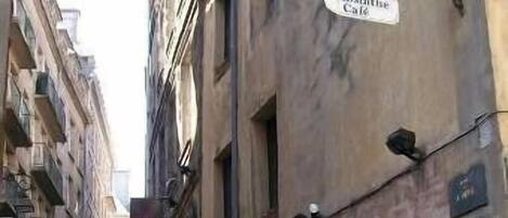 A narrow street with buildings on either side, one of which has a sign for 'La Absinthe Cafe'.