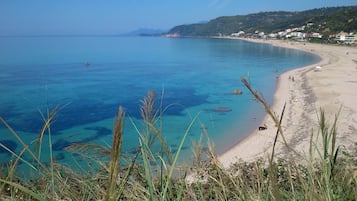 Di pantai, pasir putih, dan payung pantai