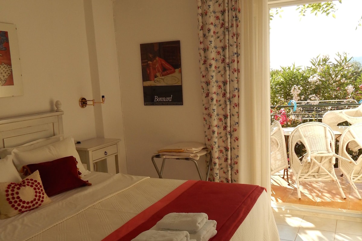 Una habitación de hotel con una cama, una mesita, una silla y vistas al exterior.