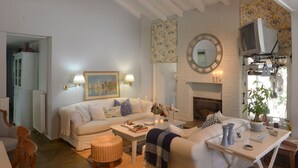 Una sala de estar acogedora con un sofá blanco, una mesa de centro, una chimenea y un televisor.
