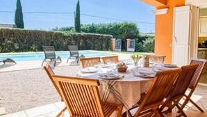 An outdoor dining area with a pool, wooden chairs, and a table set for a meal. - Recent Provencal villa, 8 rooms, all comfort with swimming pool on closed space (Cotignac, Monfort sur Argens)
