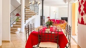 A dining area with a red tablecloth, a chandelier, and a staircase leading to another room. - Recent Provencal villa, 8 rooms, all comfort with swimming pool on closed space (Cotignac, Monfort sur Argens)