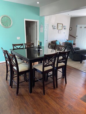 A dining area with a round table and chairs, a clock on the wall, and a door leading to another room. - Fall special, 15% off, book now before it's too late!! (Beach Haven)