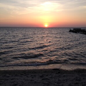 A sunset over a calm sea with a pier extending into the water. - Fall special, 15% off, book now before it's too late!! (Beach Haven)