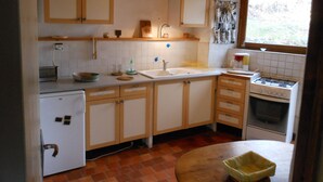 A compact kitchen with wooden cabinets, a sink, a stove, and a small refrigerator. - Gîte de Chapelèche "Les Genêts" (Gluiras)