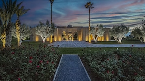 A large building with a central entrance, surrounded by well-maintained gardens and palm trees. - ADNAA - Luxury Villa with 2 pools, sauna, hammam, tennis court & home cinema (Marrakech)