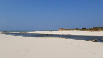 Une vaste plage de sable fin, avec un ciel dégagé et une mer calme.