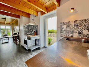 A modern kitchen with a large island, a built-in oven, and a patterned backsplash. - Reder Mor : maison de pêcheurs 250 m de la mer (SANTEC)