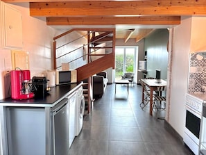 A modern kitchen with a built-in washing machine, a red coffee maker, and a microwave. There is a staircase leading to an upper level. - Reder Mor : maison de pêcheurs 250 m de la mer (SANTEC)