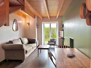 A cozy living room with a sofa, a dining table, and a striped chair. - Reder Mor : maison de pêcheurs 250 m de la mer (SANTEC)