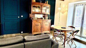 A cozy living room with a dark blue door, a wooden cabinet with glass doors, a round wooden table, and a gray sofa. - Reder Mor : maison de pêcheurs 250 m de la mer (SANTEC)