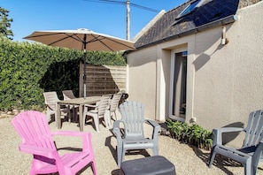 A patio area with outdoor furniture, including a table and chairs, and a large umbrella providing shade.