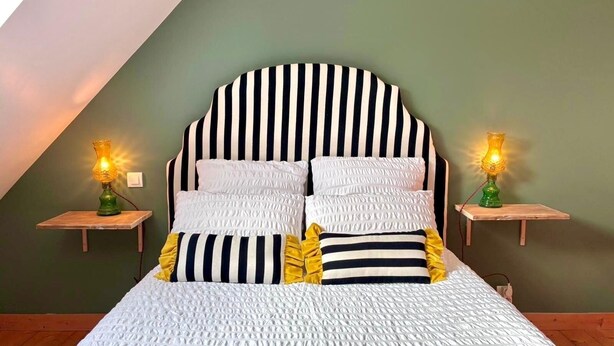 A bed with a striped headboard, two bedside tables with lamps, and a green wall. - Reder Mor : maison de pêcheurs 250 m de la mer (SANTEC)