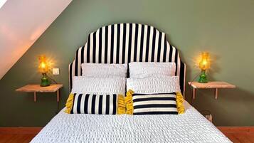 Un lit avec une tête de lit à rayures, deux tables de chevet avec des lampes et un mur vert.