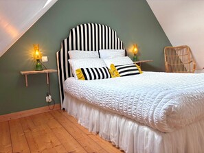 Une chambre à coucher avec une tête de lit à rayures, une literie blanche et deux lampes de chevet.