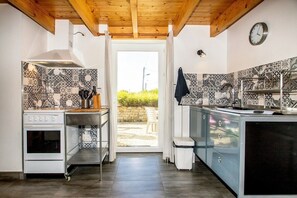A kitchen with a built-in oven, a sink, and a window leading to an outdoor area. - Reder Mor : maison de pêcheurs 250 m de la mer (SANTEC)