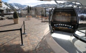 A chairlift at Riverfront Village with a view of snow-covered mountains.