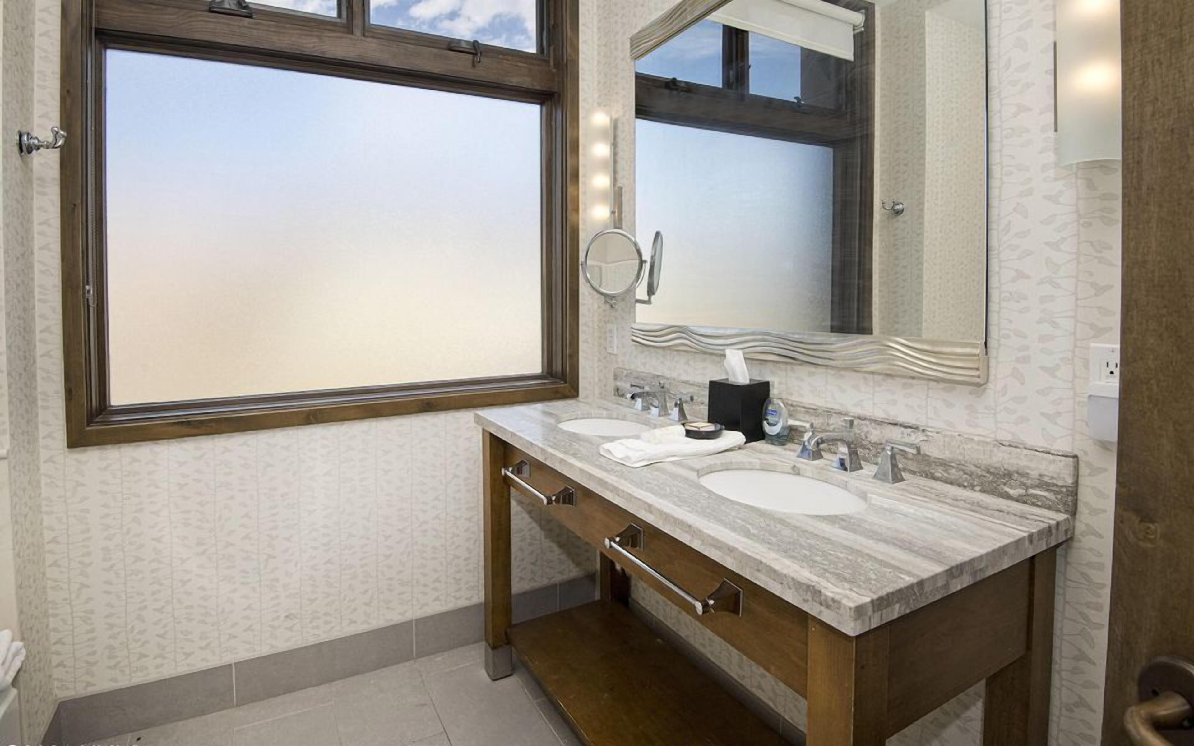 A bathroom with two sinks, a mirror, and a window.