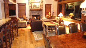 Un salon chaleureux avec une cheminée en pierre, des meubles en bois et une grande fenêtre.