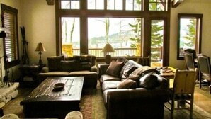Un salon confortable avec une grande fenêtre, un canapé, une table basse et une lampe.