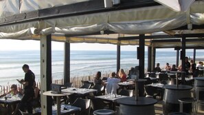 An outdoor dining area with tables and chairs, overlooking the ocean.